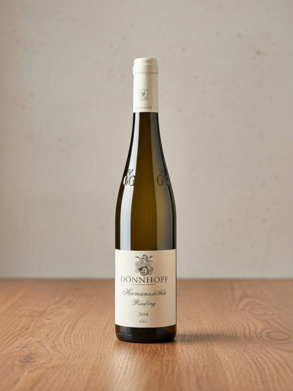 Goldener Zwilling Dönnhoff Hermannshöhle GG Riesling 2016 Weißweinflasche auf Holztisch vor neutralem Hintergrund