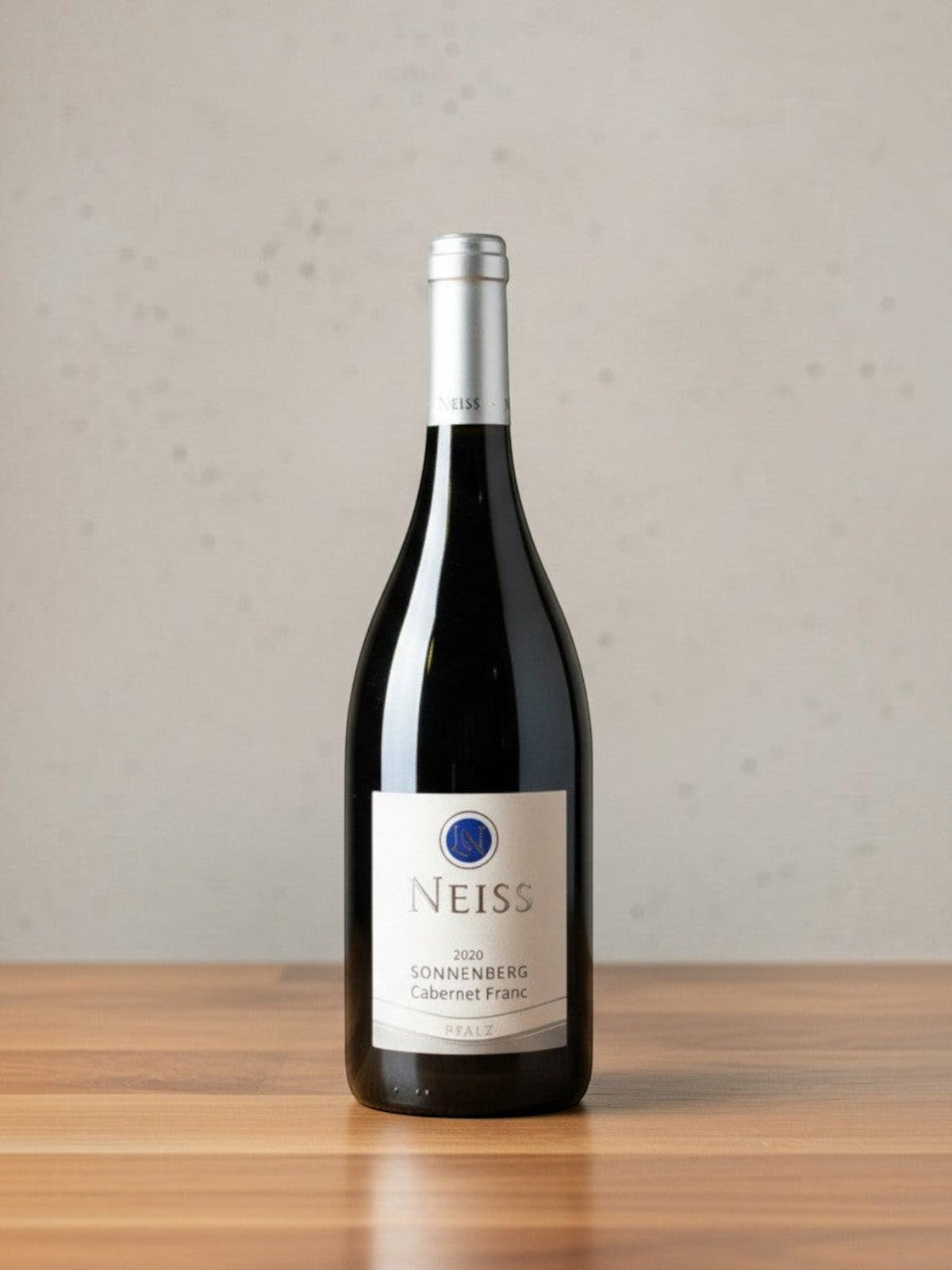 Goldener Zwilling Neiss Cabernet Franc Sonnenberg 2020 Rotweinflasche auf einem Holztisch vor neutralem Hintergrund