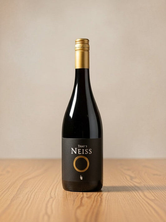 Goldener Zwilling Neiss That's Neiss Rotwein 2023 in einer eleganten Flasche mit goldenem Verschluss auf Holztisch